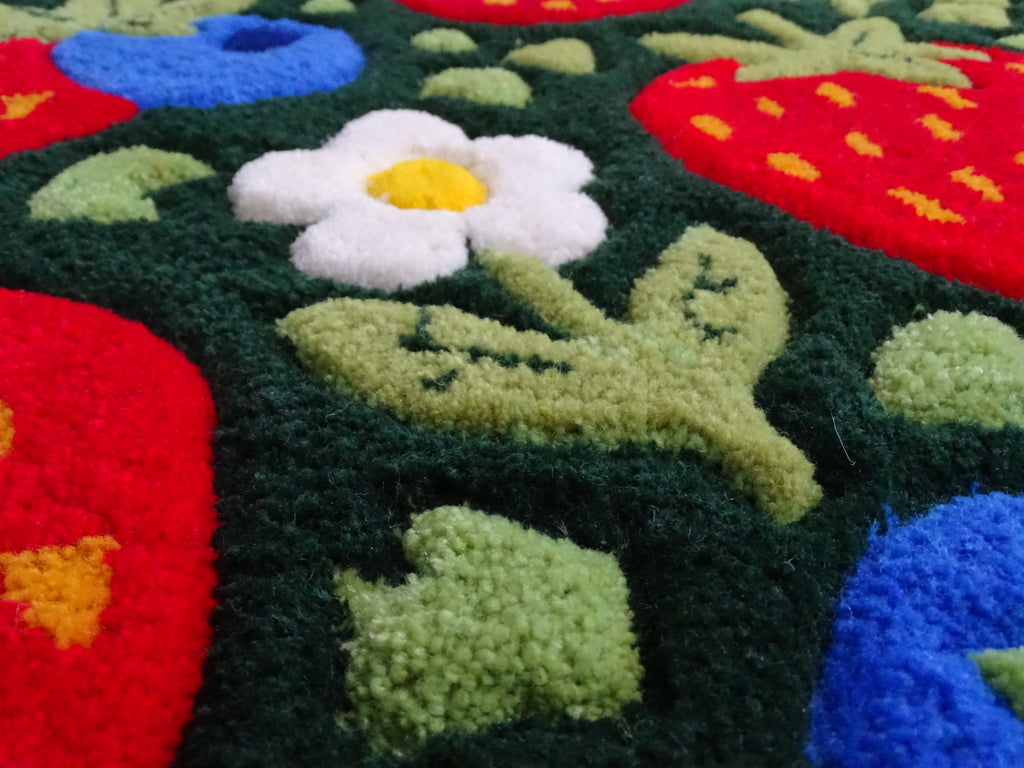 Close-up of a handmade children’s rug showing raised strawberry and blueberry details, carved 3D texture, made from 100% natural Baltic sheep wool