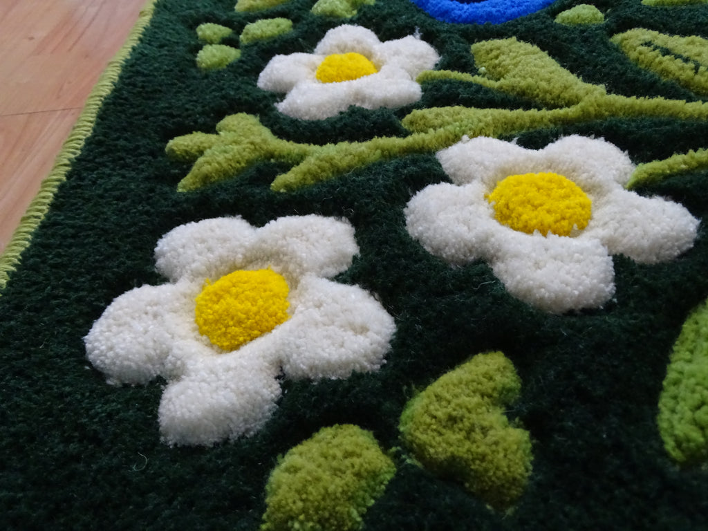 Detailaufnahme eines handgefertigten Kinderteppichs mit erhabenen Erdbeer- und Blaubeer-Motiven, 3D-geschnitzter Struktur aus 100 % natürlicher baltischer Schafwolle