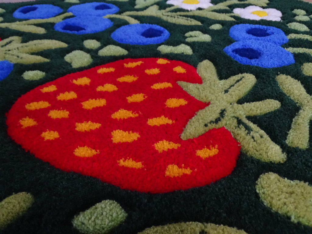 Close-up of a handmade children’s rug showing raised strawberry and blueberry details, carved 3D texture, made from 100% natural Baltic sheep wool