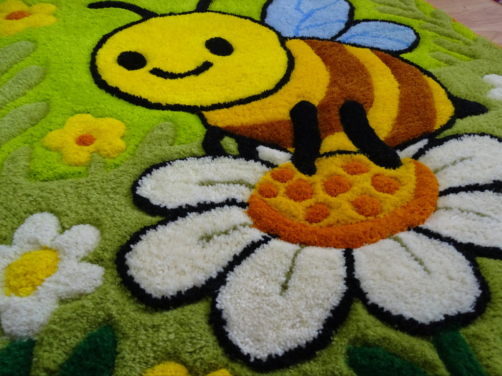 Nahaufnahme der 3D-geschnitzten Schrift auf personalisiertem Wollteppich mit Bienenmotiv, handgefertigt in Lettland.