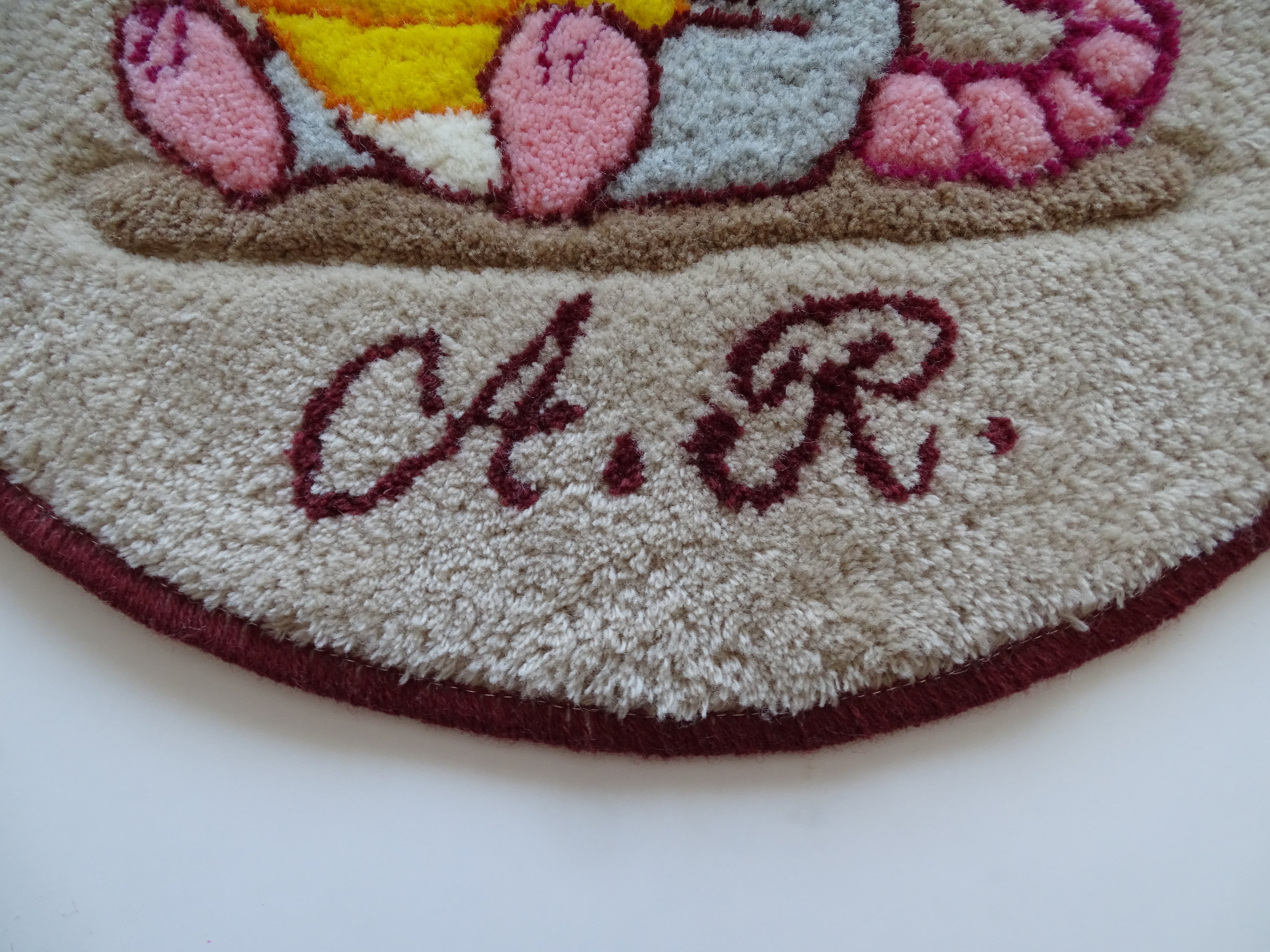 Close-up of hand-tufted wool rug texture showing dense, soft pile and carved detailing of the mouse design.