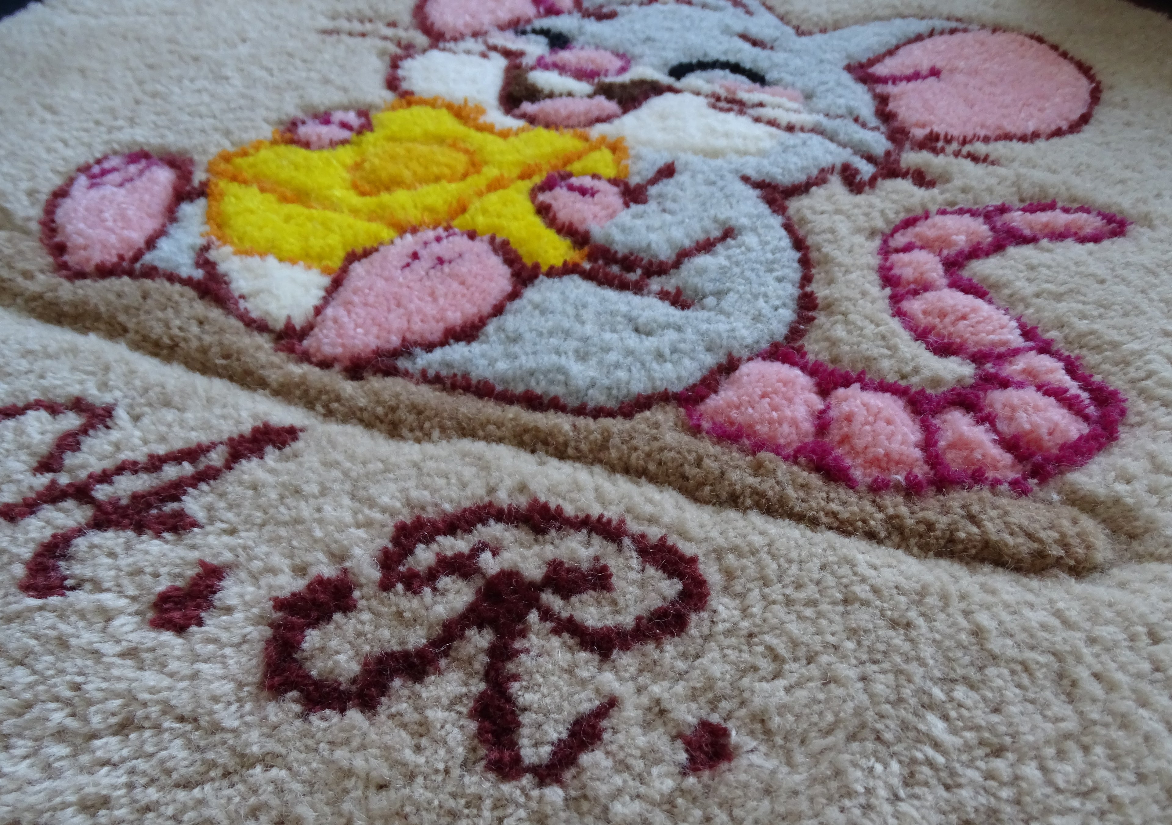 Close-up of hand-tufted wool rug texture showing dense, soft pile and carved detailing of the mouse design.