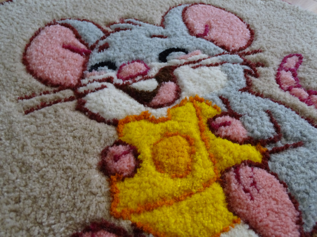Close-up of hand-tufted wool rug texture showing dense, soft pile and carved detailing of the mouse design.