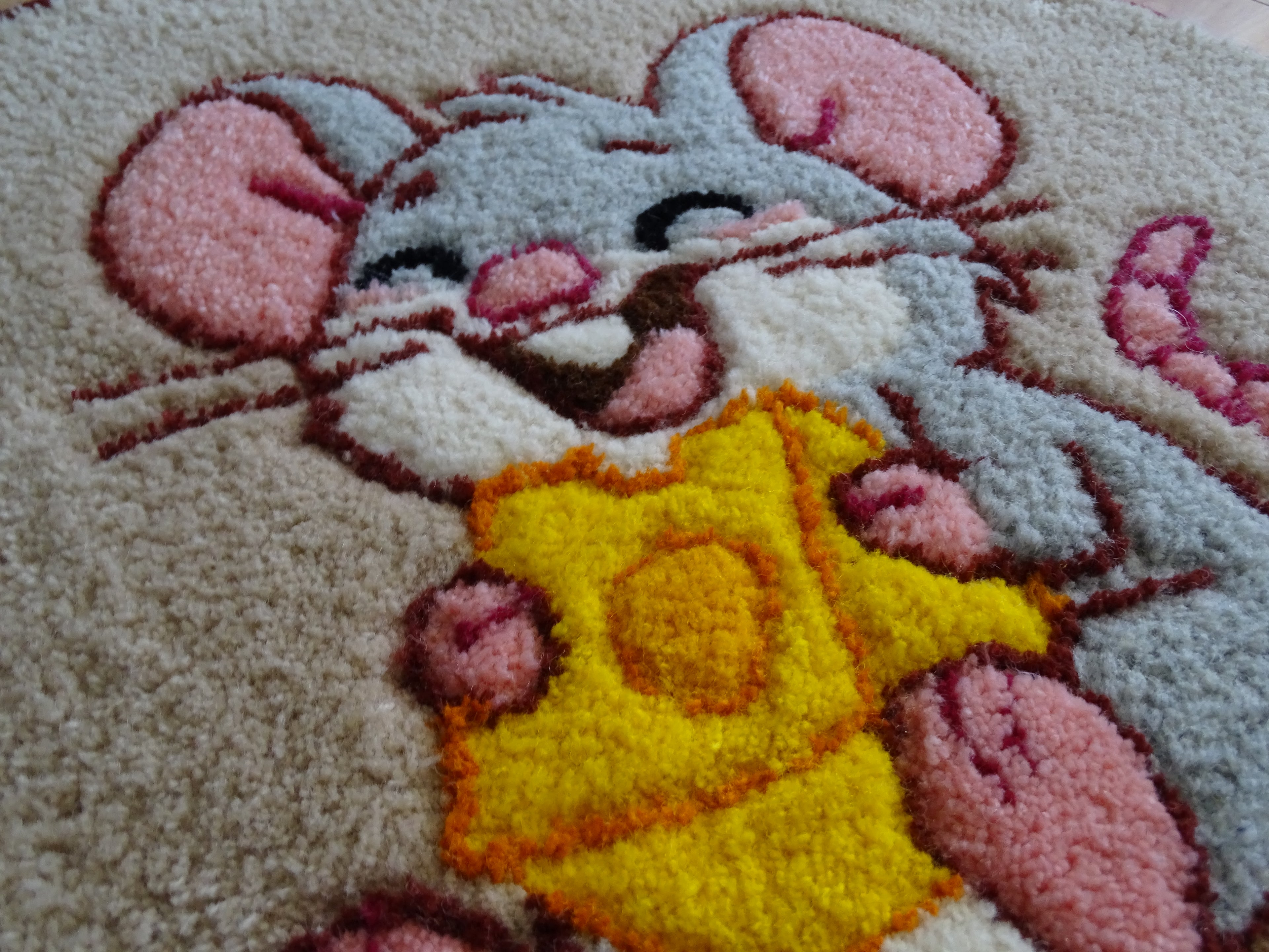 Close-up of hand-tufted wool rug texture showing dense, soft pile and carved detailing of the mouse design.