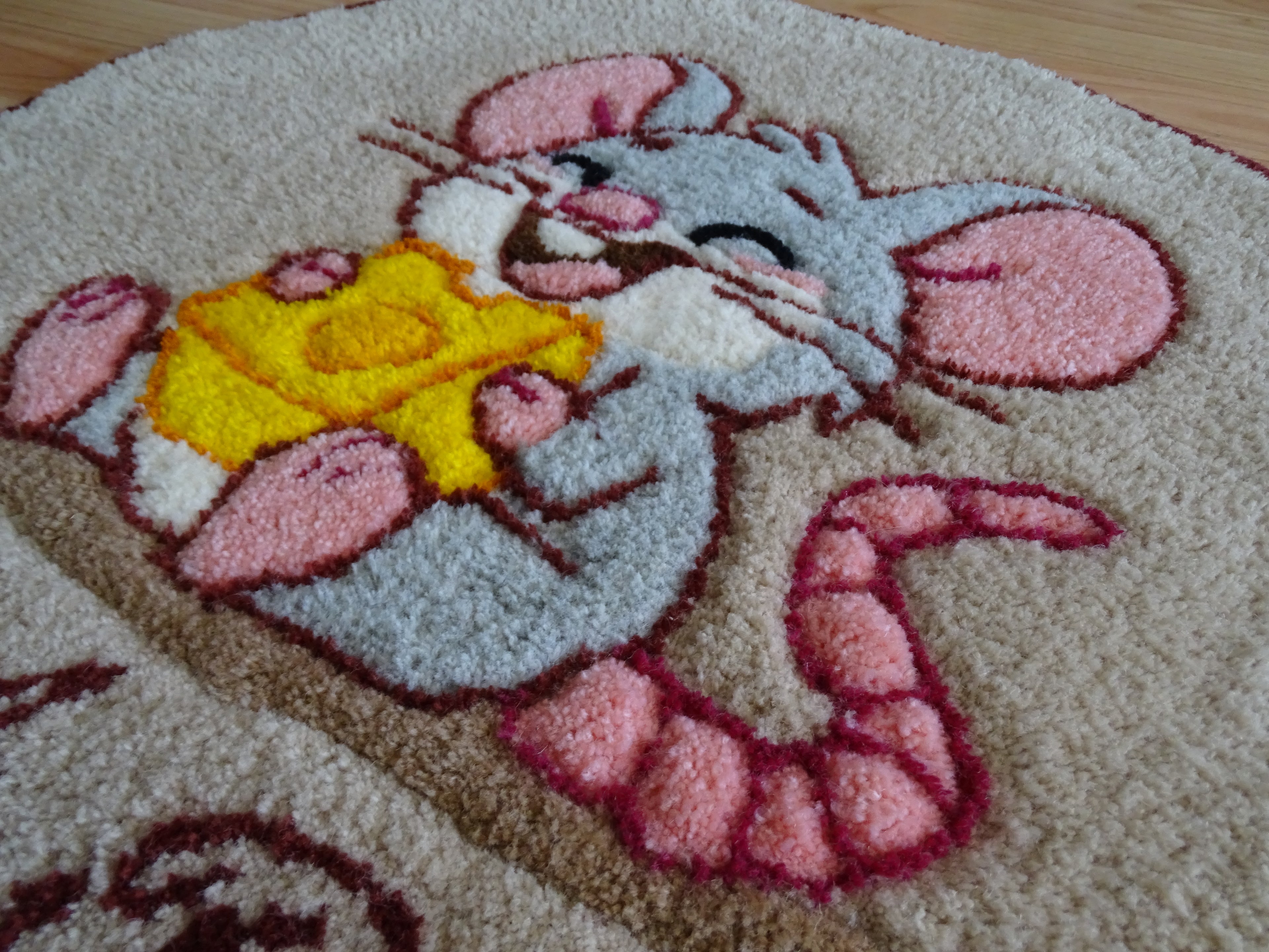 Close-up of hand-tufted wool rug texture showing dense, soft pile and carved detailing of the mouse design.