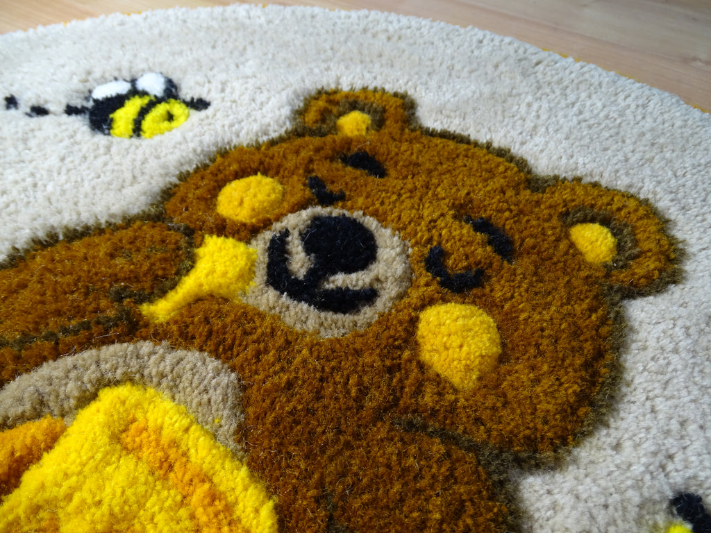 Round hand-tufted wool rug with a carved 3D teddy bear motif and personalized initials, made from 100% natural wool with a contrasting stitched border.