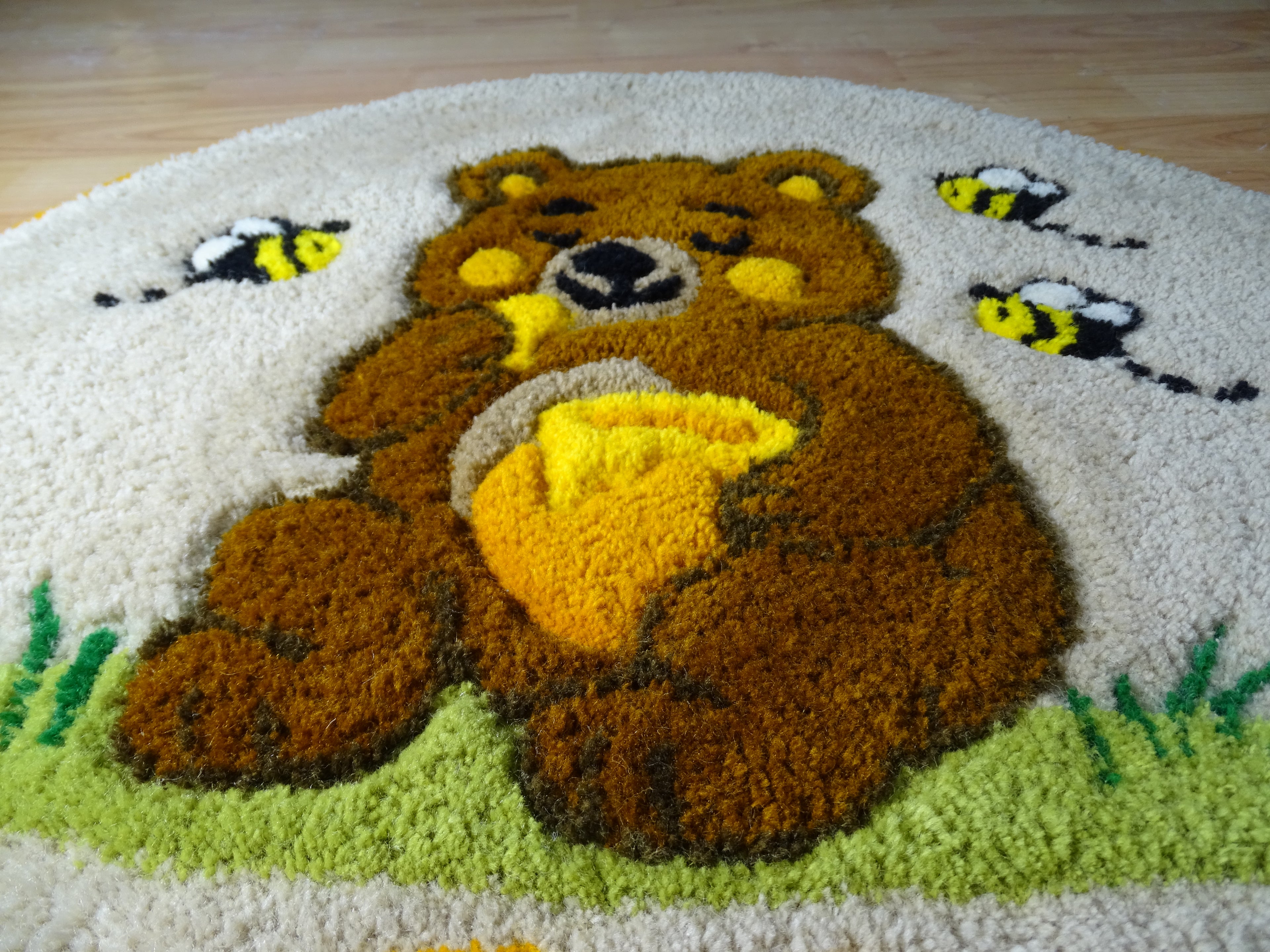 Round hand-tufted wool rug with a carved 3D teddy bear motif and personalized initials, made from 100% natural wool with a contrasting stitched border.