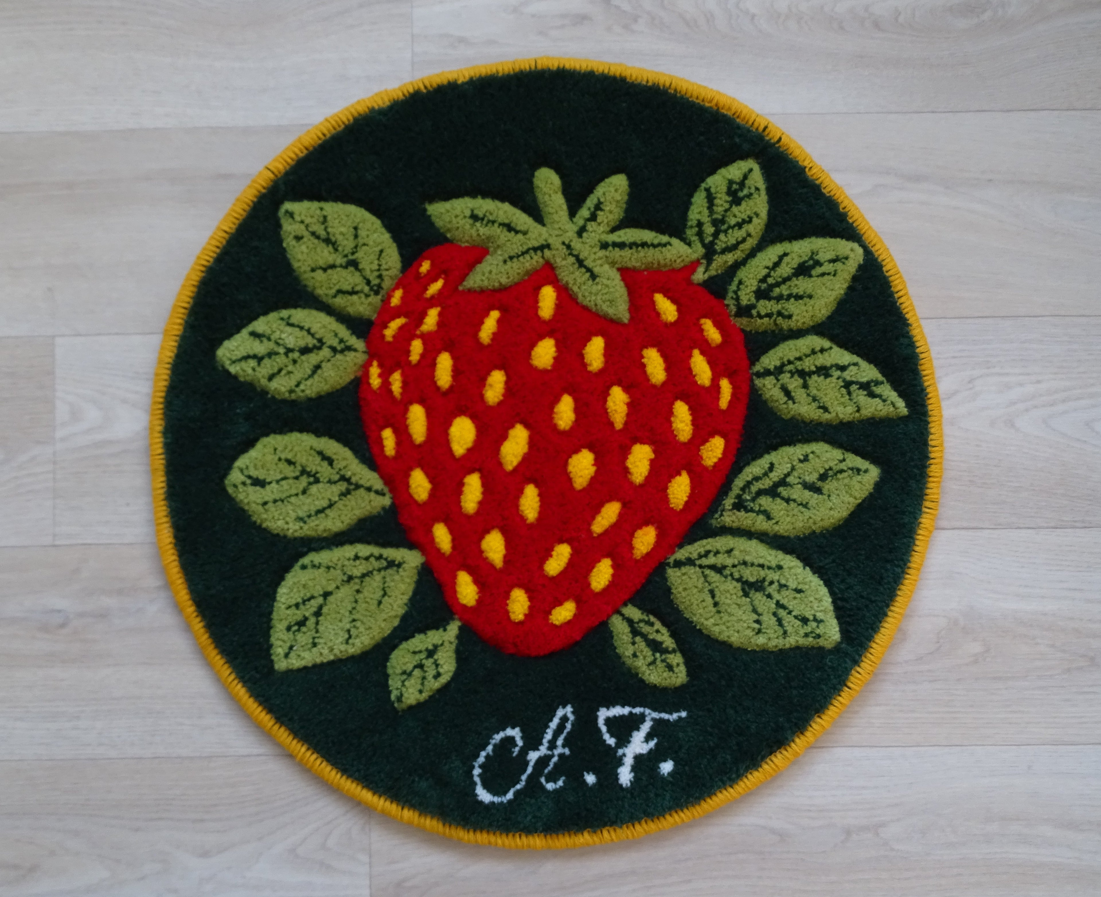Round hand-tufted wool rug with strawberry motif, personalized with initials, made from natural wool with linen backing.