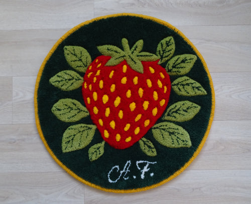 Round hand-tufted wool rug with strawberry motif, personalized with initials, made from natural wool with linen backing.