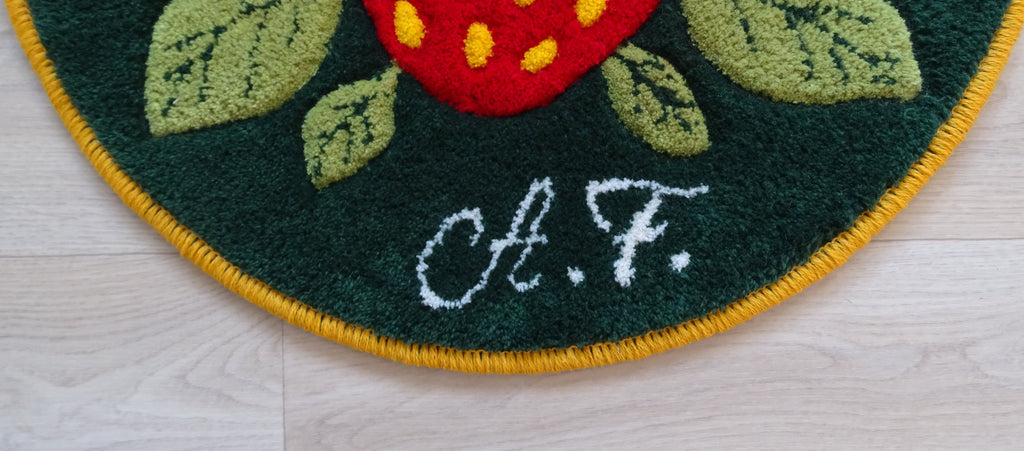 Round hand-tufted wool rug with strawberry motif, personalized with initials, made from natural wool with linen backing.